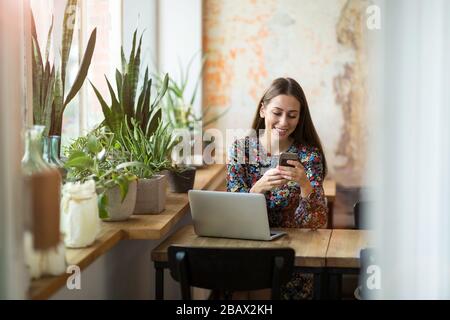 Giovane donna con il computer portatile in cafe Foto Stock