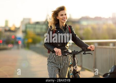 Giovane donna con bicicletta al tramonto Foto Stock