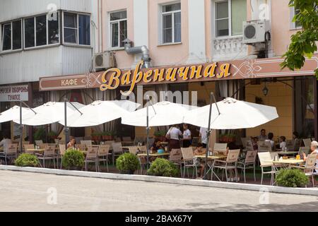 TUAPSE, RUSSIA-LUGLIO 2018: Tavoli e sedie sotto ombrelloni sono all'esterno del ristorante. Un'area pranzo all'aperto con caffè che cucinano gnocchi dolci. IT Foto Stock