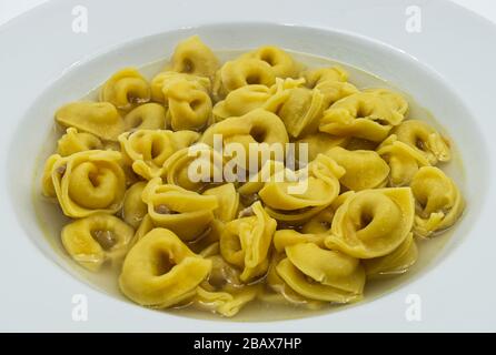 Tortellini in brodo (brodo) isolati su bianco. Pasta tradizionale italiana Foto Stock