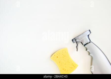 Detergente spray in flacone grigio. Vista dall'alto del prodotto detergente e della spugna su sfondo bianco. Primo piano. Spazio di copia. Foto Stock