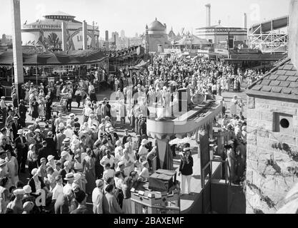 La folla di fiabe esplora la zona fieristica e guarda gli artisti in un palcoscenico sul Midway durante il Century of Progress International Exposition, conosciuto anche come Chicago World's Fair, Chicago, Illinois, 1933. (Foto di Burton Holmes) Foto Stock