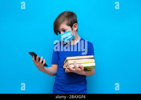 Istruzione a distanza per il periodo di coronavirus. Insegnare agli studenti in remoto durante l'isolamento e la quarantena. ragazzo di 9 anni con libri di testo Foto Stock