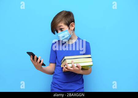 Istruzione a distanza per il periodo di coronavirus. Insegnare agli studenti in remoto durante l'isolamento e la quarantena. ragazzo di 9 anni con libri di testo Foto Stock