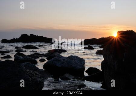 Vista del tramonto o del sole stellare sulla roccia con il tramonto sullo sfondo dell'oceano atlantico, Punta Ballena, Maldonado, Uruguay Foto Stock