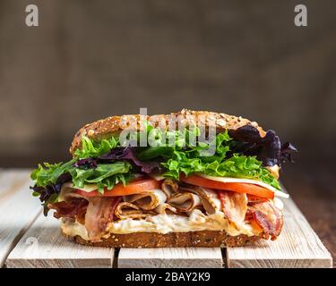 Panino di blt appena fatto su una superficie di legno chiaro slattato con un tessuto leggero fondo leetuce formaggio tomatoe pancetta maionaise pane di segale Foto Stock