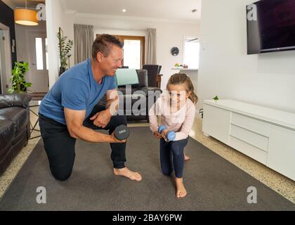 Arresto COVID-19. Padre e figlia in quarantena esercitandosi insieme con dumbbells. Vantaggi dell'attività fisica durante il blocco. Rimani a casa, Foto Stock