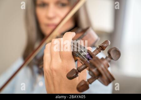 Immagine ravvicinata di una donna che suona il violino. Profondità di campo bassa, messa a fuoco sulle dita Foto Stock