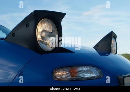 Primo piano dei fari a scomparsa, blu Mazda MX-5 mk1 Foto Stock