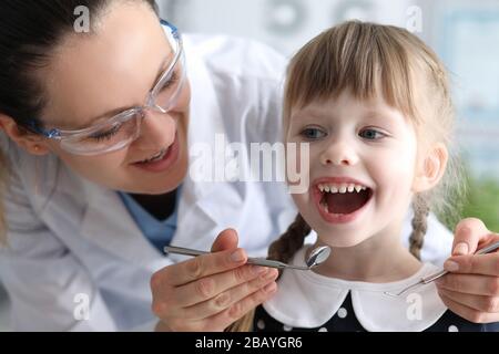 Il dentista della donna esamina i denti nella clinica al bambino Foto Stock