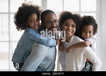 Ritratto di etnia africana genitori piggybacking figlio e figlia al chiuso Foto Stock