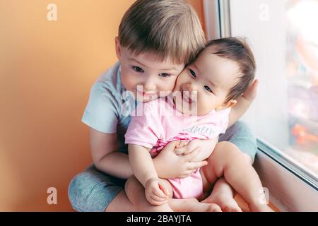 fratello maggiore che abbraccia la sua sorella bambino giocando e sorridendo insieme. concetto di famiglia amore proteggere Foto Stock