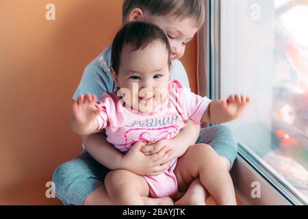 fratello maggiore che abbraccia la sua sorella bambino giocando e  sorridendo insieme. concetto di famiglia amore proteggere Foto stock - Alamy