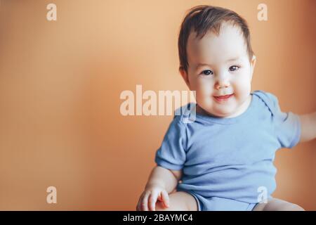 Bella bambina o ragazzo con capelli scuri sorridenti su un colore di sfondo arancione brillante del 2019 con spazio per testo felice sorriso guardare la fotocamera Foto Stock