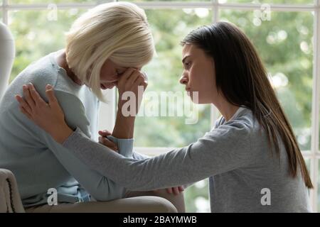 Amorevole figlia adulto conforto turbato mamma matura Foto Stock