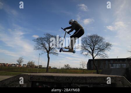 Giovane scooter rider, inghilterra, regno unito, skate, skatepark, rampe, trucchi, scooter, parco, salti, acrobazie. Foto Stock