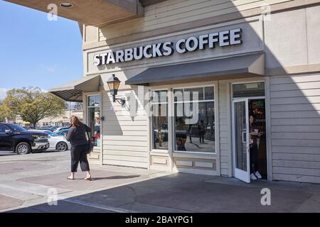 Una donna esce da una caffetteria Starbucks con una tazza da caffè da non fare a Redwood City, California. Foto Stock