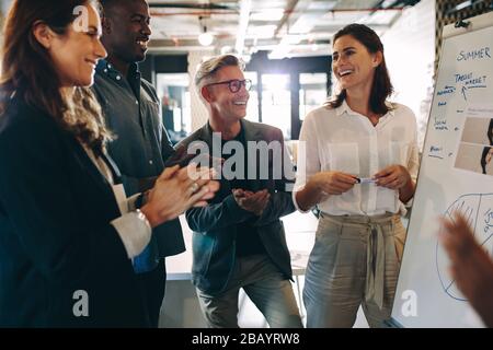 Gruppo di uomini d'affari che apprezzano la presentazione al compagno di squadra in ufficio. Il team aziendale batte le mani dopo una presentazione di successo. Foto Stock