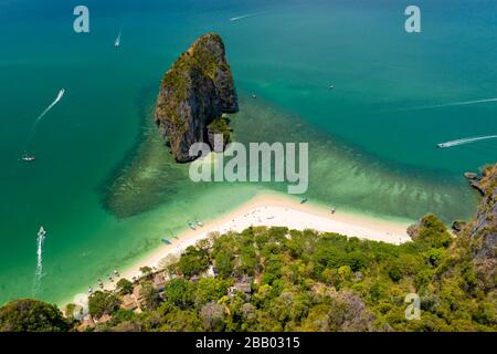 Veduta aerea del drone di una splendida spiaggia di sabbia tropicale circondata da giungla verde e torreggianti scogliere. (Phra Nang Beach, Krabi, Tailandia) Foto Stock