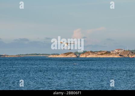 Un idrovolante giallo e bianco Cessna 172 Skyhawk che parte tra le isole dell'arcipelago di Kragerø sulla costa meridionale della Norvegia. Foto Stock