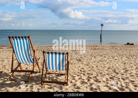 Sedie a sdraio a strisce blu e bianche su un soleggiato pomeriggio autunnale su Avon Beach, Inghilterra, Regno Unito. Foto Stock