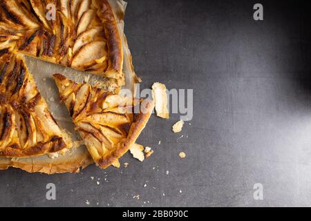 Torta di mele cotta a casa su un tavolo di pietra scura con una tazza di caffè sul lato. Vista dall'alto. Foto Stock