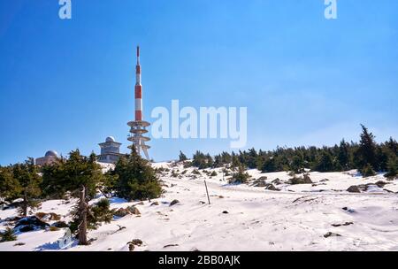 Antenna radio architettura Torre sulla cima di una montagna con cielo blu in luminoso paesaggio invernale neve. Brocken Plateau, Parco Nazionale delle Montagne Harz Foto Stock