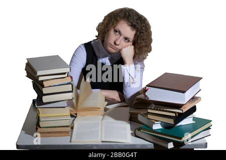 Curly ragazza è seduta al tavolo con enorme mucchio di libri isolati su sfondo bianco Foto Stock