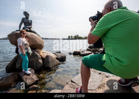 Turista in posa per la foto accanto alla statua della Sirenetta a Copenhagen, Danimarca, Europa Foto Stock