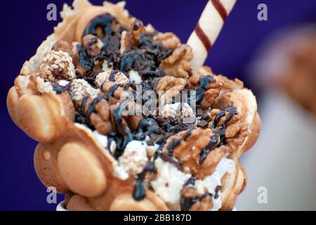 Tazza con deliziosi waffle a bolle dolci su sfondo scuro Foto Stock