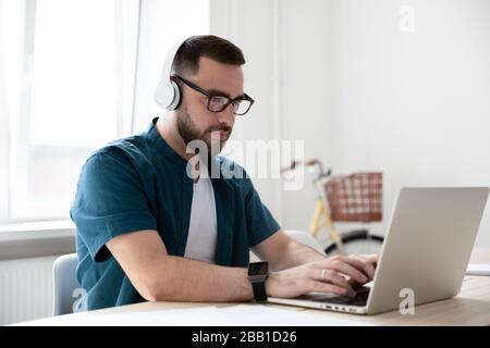 I dipendenti maschi in cuffie wireless lavorano su un notebook Foto Stock