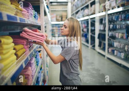 Bella donna di ispezione e acquisto di asciugamani nel supermercato Foto Stock