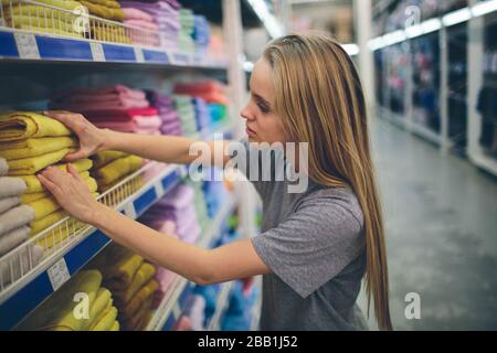 Bella donna di ispezione e acquisto di asciugamani nel supermercato Foto Stock