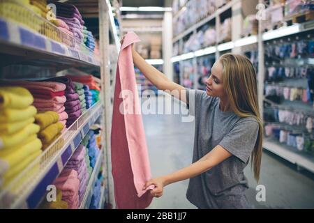 Bella donna ispezionare e comprare asciugamani in supermercato. Foto Stock