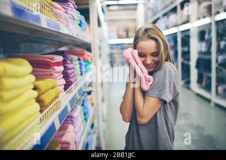 Bella donna ispezionare e comprare asciugamani in supermercato. Foto Stock