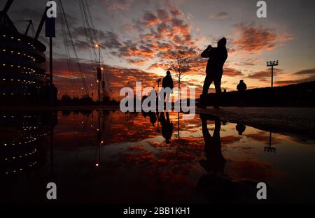 I fan arrivano allo Stadio Etihad mentre il sole tramonta prima della partita Foto Stock