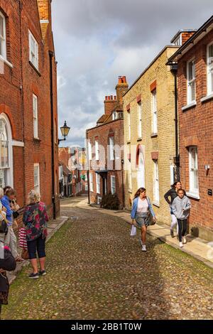 I visitatori di Rye camminano su West Street Rye, una strada acciottolata, e alcuni aspettano di andare nella proprietà National Trust, Lamb House, East Sussex, UK Foto Stock