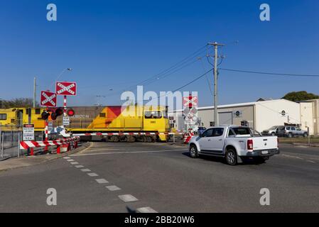 Il traffico si fermò a un livello di attraversamento ferroviario a Rockhampton Queensland Australia per un treno merci in direzione nord. Foto Stock