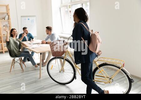 Biracial giovane donna di corsa dipendente bici in ufficio Foto Stock