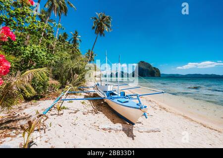 La barca della Banca delle Filippine. Tradizionale barca da pesca sulla spiaggia a mezzogiorno luminoso sole. El Nido, Palawan Foto Stock