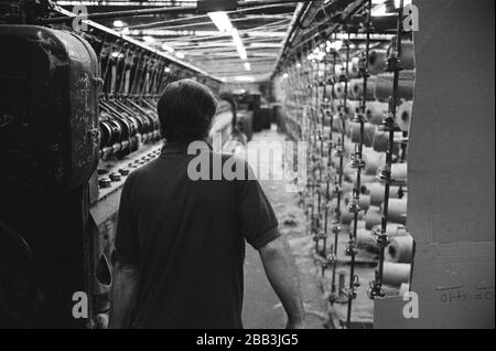 Un lavoratore che supervisiona una macchina al mulino Tay Spinners di Dundee, in Scozia. Questo stabilimento è stato l'ultimo filatoio di iuta in Europa quando è stato chiuso per l'ultima volta nel 1998. La città di Dundee era stata famosa per la storia dei tre 'JS' - juta, jam e giornalismo. Foto Stock