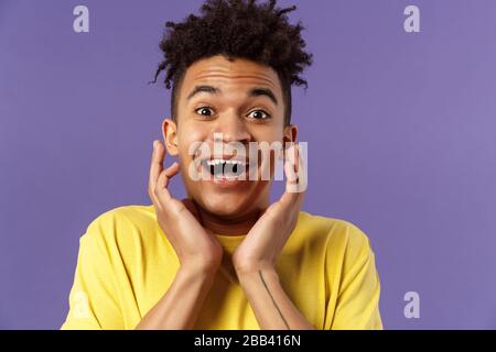 Primo piano ritratto di giovanotto estremamente felice e entusiasta sentire fantastiche notizie, guardando sorpreso ed eccitato, toccante volto nella gioia, sorridente ottimista Foto Stock