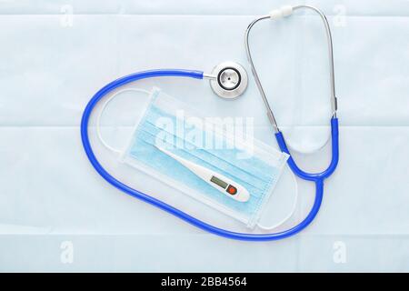 Maschera medica, termometro, misurazione della temperatura corporea, controllo della febbre. Coronovirus Covid-19 Diagnostics.maschera chirurgica per la protezione del viso su sfondo blu Foto Stock