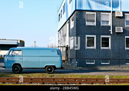 Bus VW azzurro accanto alle rotaie nel porto di spedizione di Düsseldorf . Foto Stock