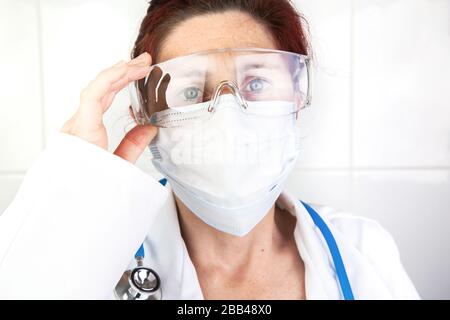 Primo piano ritratto di un infermiere o medico che regola i suoi occhiali protettivi Foto Stock