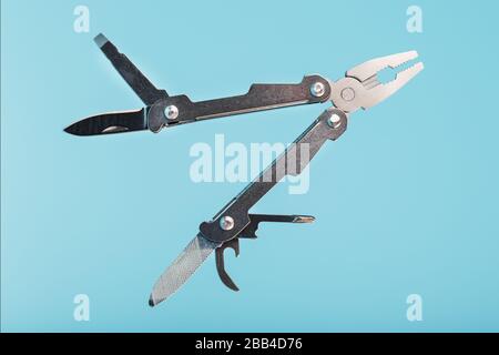Lo strumento multifunzione multitool si trova su uno sfondo blu. Il concetto di un multi-utensile espanso con spazio libero. Foto Stock