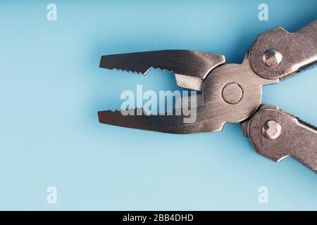 Lo strumento multifunzione multitool si trova su uno sfondo blu. Il concetto di un multi-utensile espanso con spazio libero. Foto Stock