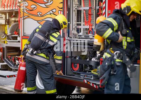 Vigili del fuoco in uniforme davanti al camion antincendio che va a salvare e proteggere. Emergancy , pericolo, concetto di servise. Foto Stock