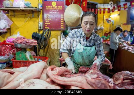 Una donna lavora con carne di manzo cruda in un mercato Hoi An Foto Stock