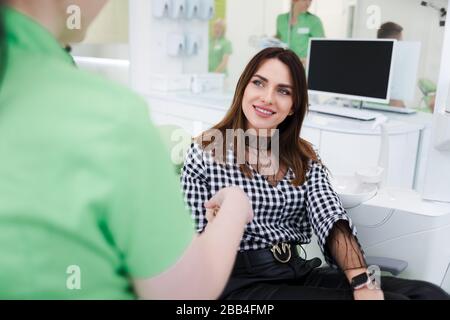 Bella donna saluta con medico dentista. Paziente ambulatoriale seduto su una sedia che scuote le mani con un dentista Foto Stock